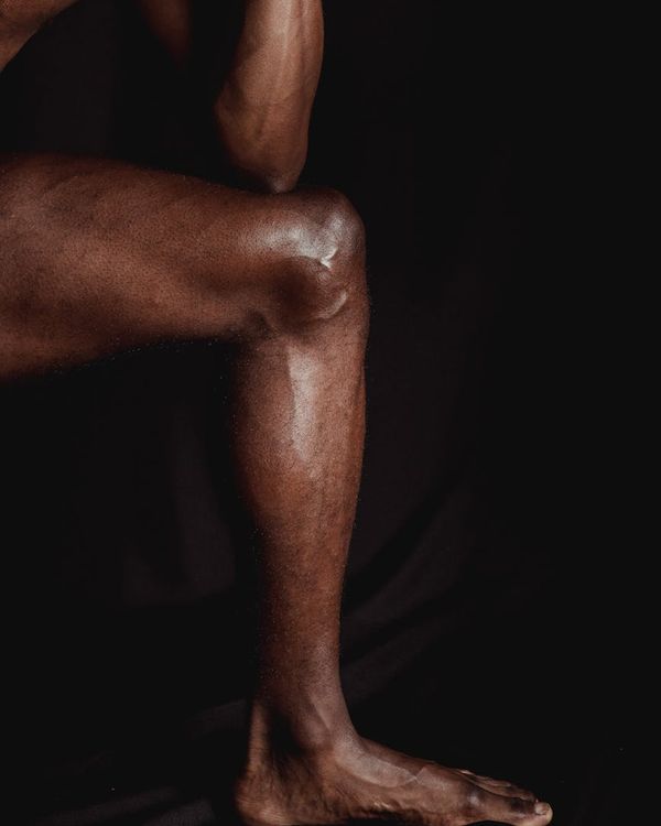 Man performing a controlled strength exercise in a minimalist dark gym.